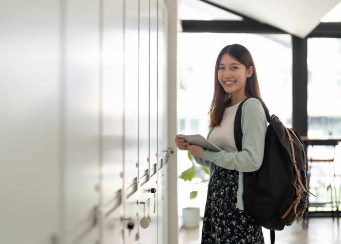 Smiling female student stood by lockers